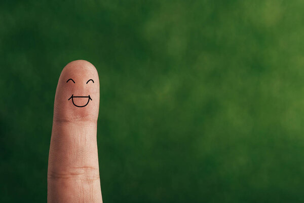 cropped view of one finger with cheerful face on green