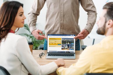 erkek ve kadın ofiste laptop ekranında rezervasyon Web sitesi ile parmaklarıyla işaret Danışmanı seçici odak