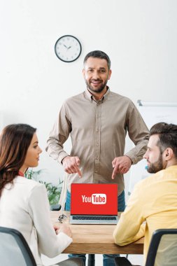 erkek ve kadın ofiste youtube Web sitesinde ekranı olan dizüstü bilgisayar, parmaklarıyla işaret Danışmanı