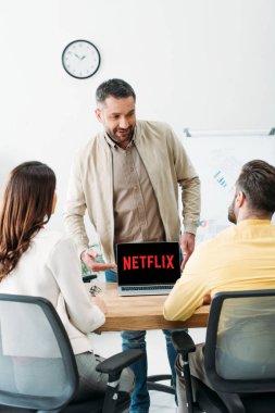 erkek ve kadın ofiste dizüstü bilgisayar ekranında netflix Web sitesi ile de el ile işaret Danışmanı