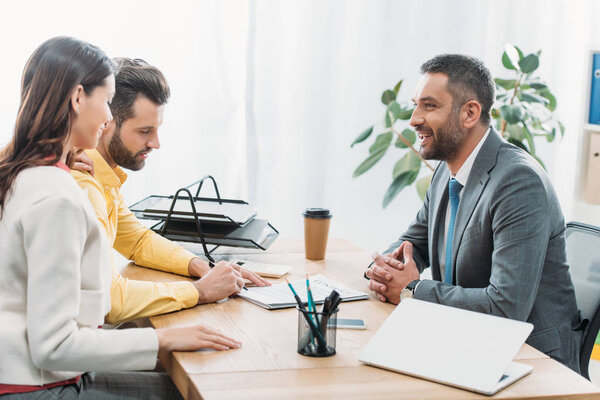 advisor and woman sitting at table wile investor signing document in office