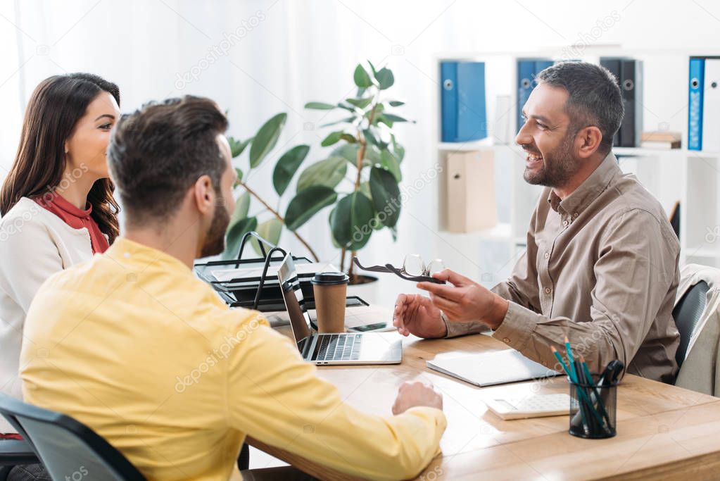 advisor sitting at table and laptop with man and woman in office