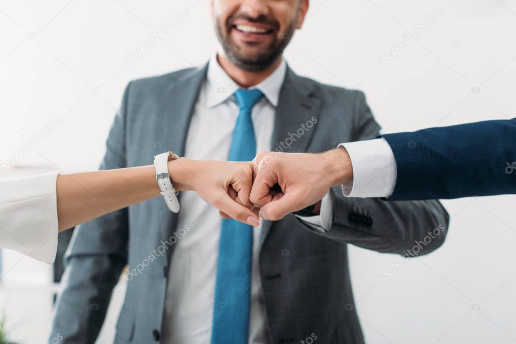 cropped view of colleagues celebrating and smiling on white backgroung