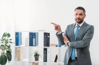 ayakta ve yan ofis parmak ile işaret eden işadamı