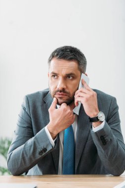 laptop ile masada oturan ve Office smartphone cep telefonu ile konuşurken işadamı konsantre