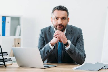 laptop ile masada oturan ve kamera Office bakarak yakışıklı işadamı
