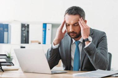 dizüstü bilgisayar ve ofis duygu baş ağrısı masada oturan yakışıklı işadamı