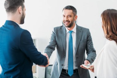 seçici odak yatırımcılar ile el sıkışan ve Doları banknot worspace alarak Danışmanı 