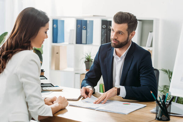 handsome advisor discussing document with investor at workspace 
