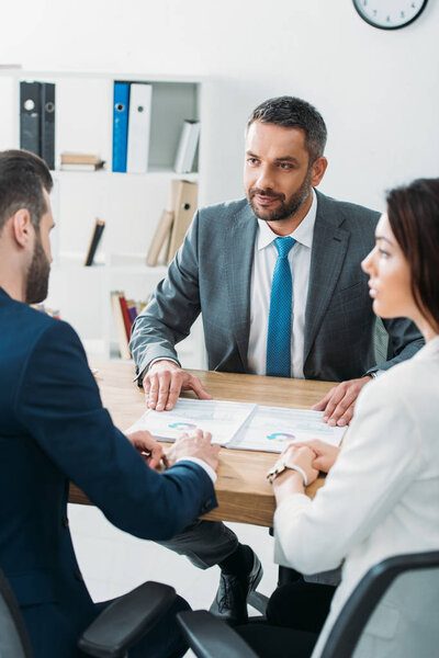 selective focus of advisor and investors in suits talking about document at worplace 