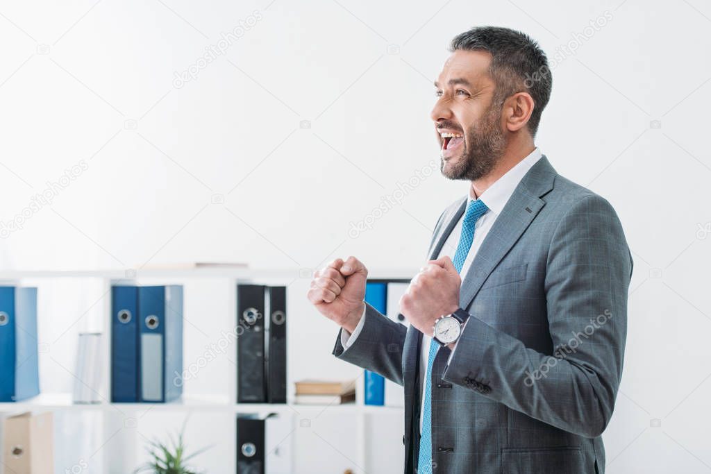 businessman standing and showing yes gesture in office
