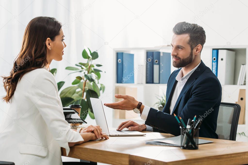 handsome advisor in suit talking with beautiful investor at office 