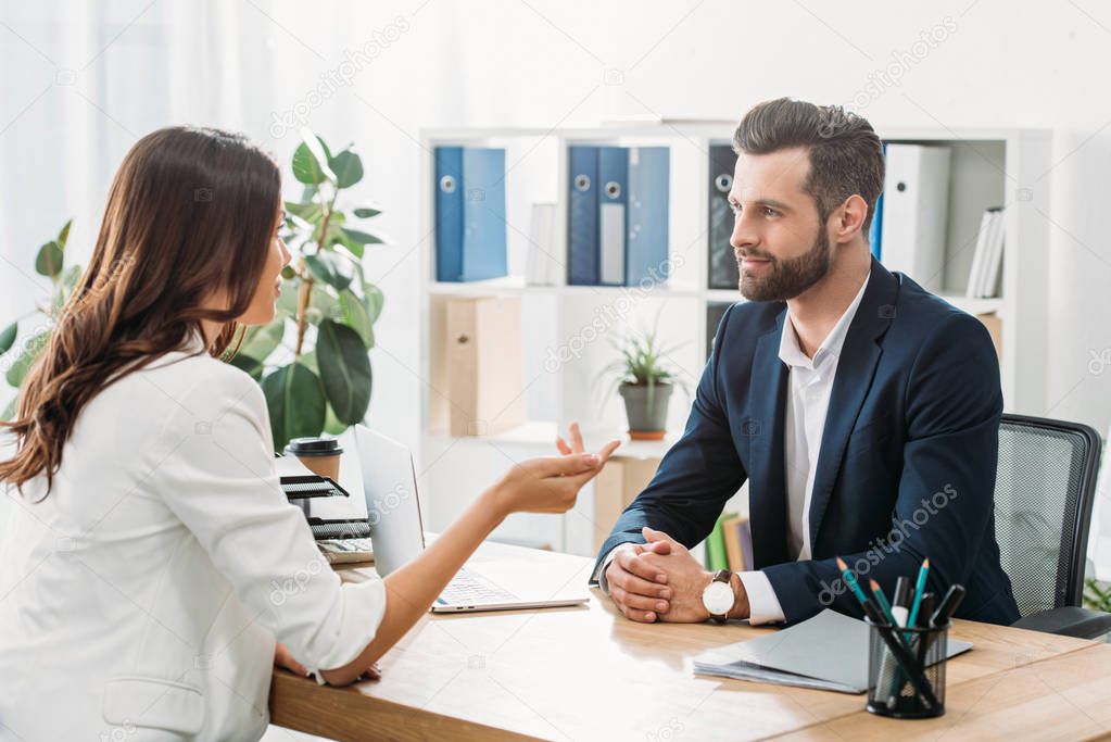 handsome advisor in suit talking with beautiful investor at office 