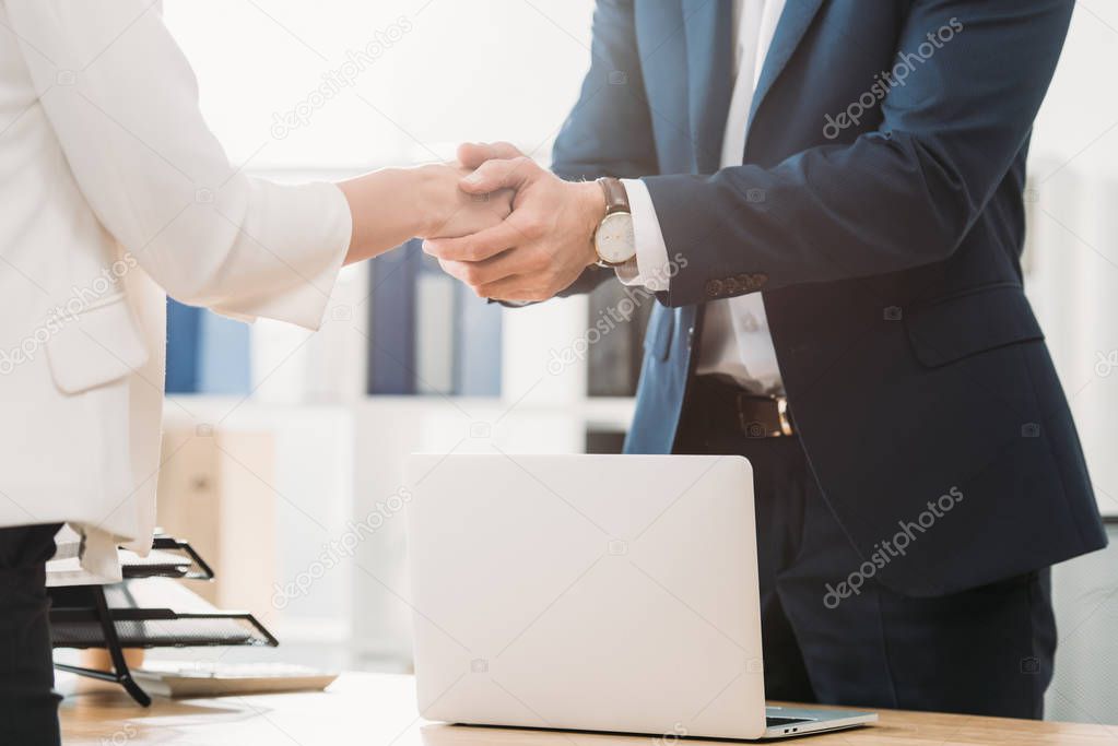 cropped view of man shaking hands with woman at office 