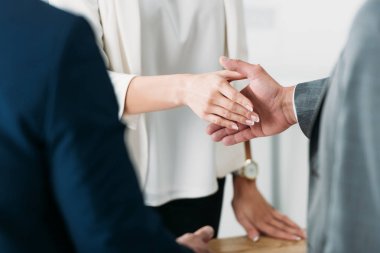 selective focus of man and woman shaking hands at office  clipart