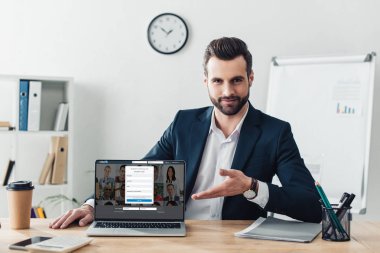 laptop ekranında LinkedIn Web sitesi ile parmaklarıyla işaret takım elbiseli yakışıklı Danışmanı 