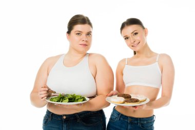 plaka üzerinde beyaz izole yeşil ıspanak yaprakları ile tutan kilolu kadın ise tabakta donut tutan ince kadın