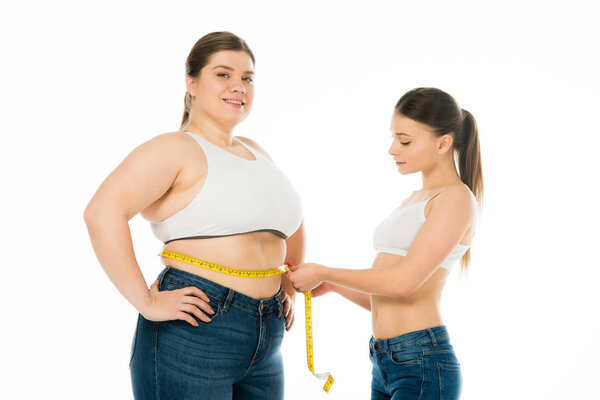 slim woman measuring waist of happy overweight woman isolated on white, body positivity concept