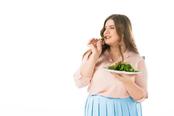 美丽的超重妇女吃新鲜的绿色菠菜叶从盘子隔离在白色 — 图库照片
