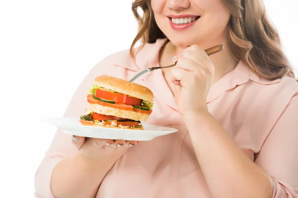 裁剪视图微笑的妇女吃美味的汉堡从盘子与叉子孤立在白色 — 图库照片