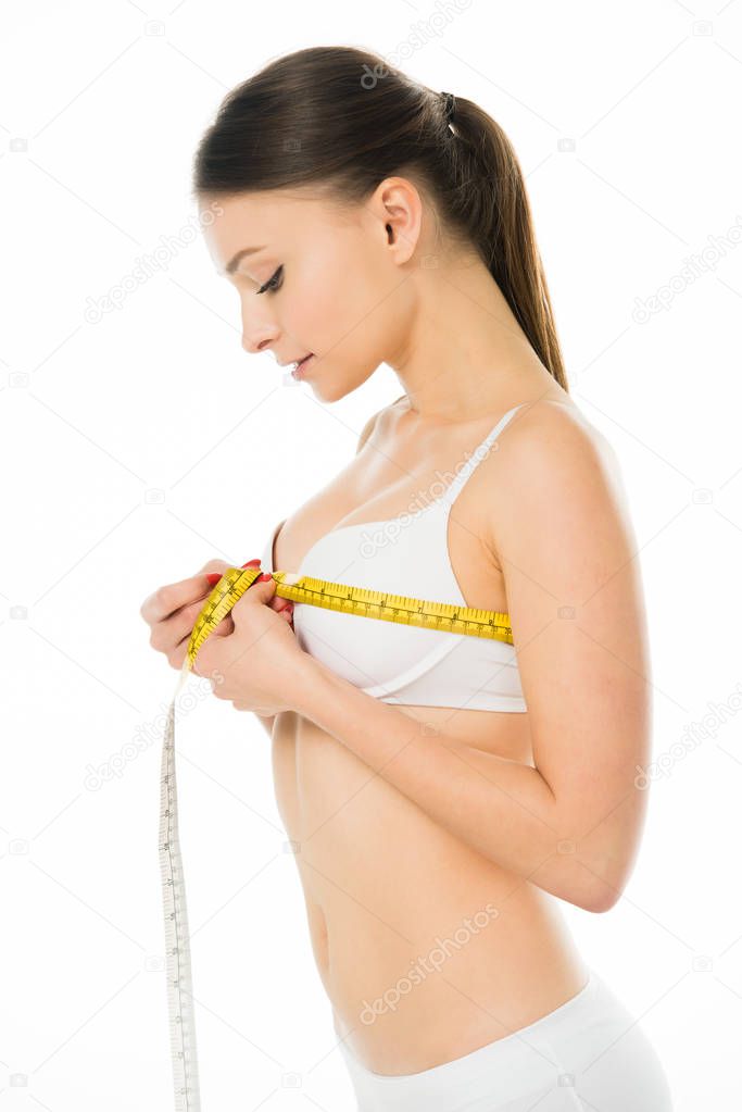 slim woman in underwear measuring bust with centimeter isolated on white