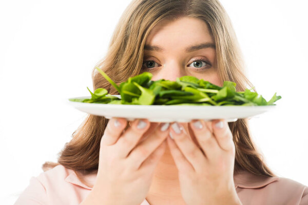 selective focus of woman holding plate with green spinach leaves isolated on white