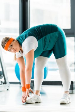 kilolu kadın fitness mat germe ve kameraya bakıyor