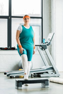 çekici artı boyutu kız spor salonunda adım platformda ayakta