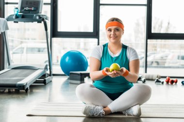 artı boyutu kadın fitness mat Spor donatımı çapraz ayaklı yakın oturan ve elma tutan
