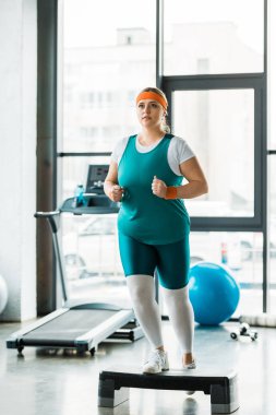 artı boyutu kız Spor donatımı yakınındaki adım platformda egzersiz