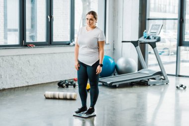 spor salonunda ölçekler üzerinde duran üzgün kilolu kadın