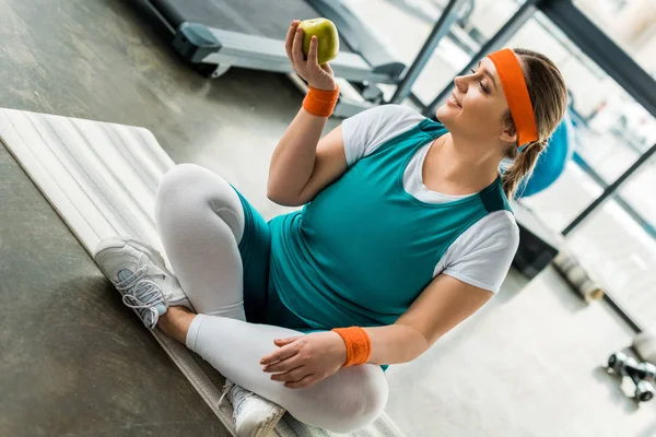 Size Woman Sitting Fitness Mat Crossed Legs Looking Apple — Stock Photo, Image