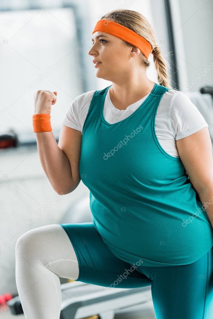 attractive plus size girl in sportswear exercising in gym