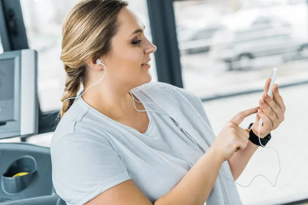 Vrolijke Overgewicht Meisje Oortelefoons Houden Van Smartphone Tijdens Het Luisteren — Stockfoto