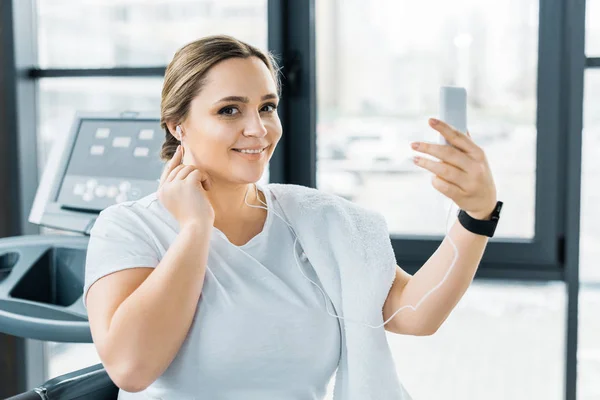 Smiling Overweight Girl Holding Smartphone While Listening Music Earphones — Stock Photo, Image