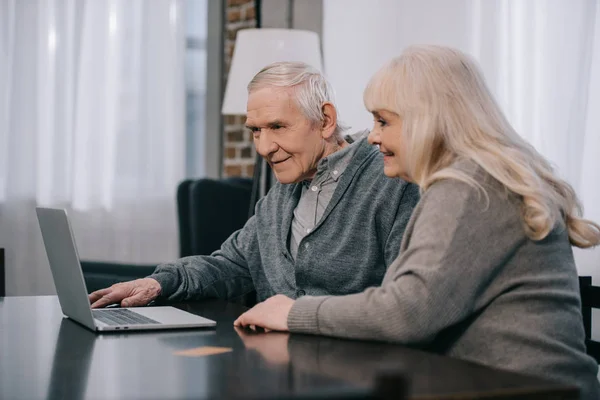 Feliz Casal Sênior Sentado Mesa Usando Laptop Casa — Fotografia de Stock