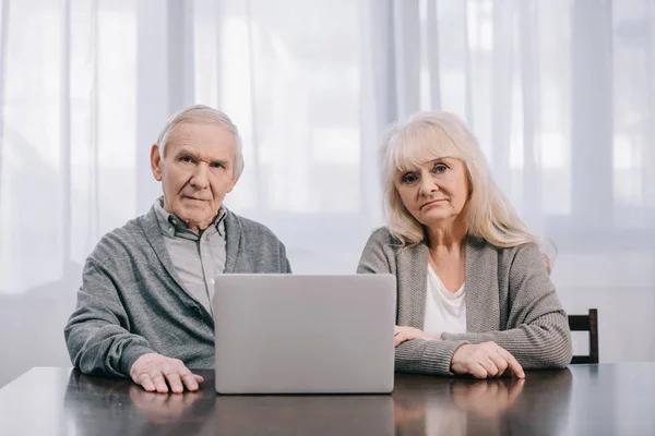 Triste Casal Sênior Sentado Mesa Olhando Para Câmera Usar Laptop — Fotografia de Stock