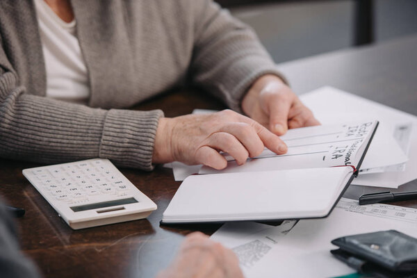 cropped view of senior woman pointing with finger at notebook with ira roth lettering