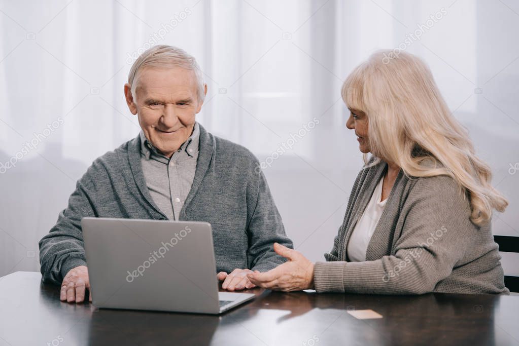 senior couple sitting at table and using laptop at home