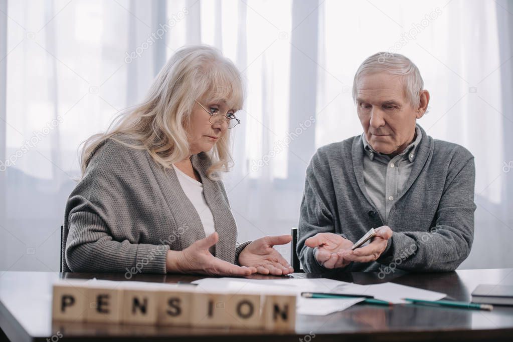 senior couple at table with word 'pension' made of wooden blocks on foreground