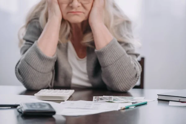 老年妇女坐在桌旁与钱和文书工作 而头痛在家里的裁剪视图 — 图库照片