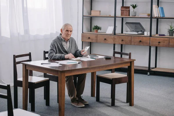 Starszy Mężczyzna Siedzący Przy Stole Papierkową Robotę Pomocą Kalkulatora Podczas — Zdjęcie stockowe