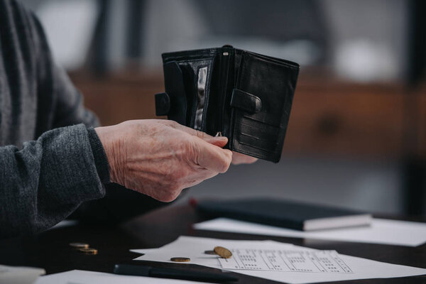 selective focus of male pensioner sitting at table with paperwork and counting money