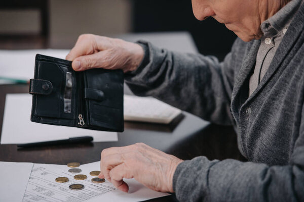 male pensioner sitting at table with paperwork and counting money