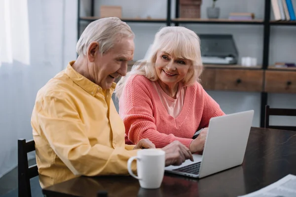 Sorridente Coppia Anziana Abiti Casual Utilizzando Computer Portatile Mentre Seduto — Foto Stock
