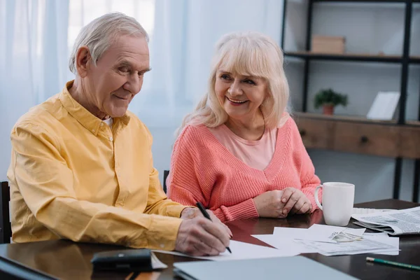 Glückliches Seniorenpaar Sitzt Tisch Und Füllt Hause Unterlagen Aus — Stockfoto