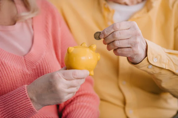 Cropped View Senior Couple Putting Coin Yellow Piggy Bank — Stock Photo, Image