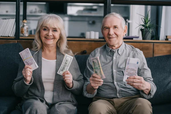 Happy Senior Couple Sitting Couch Looking Camera Holding Euro Dollar — Stock Photo, Image