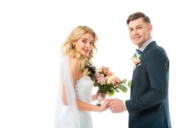 güzel gelin ve el ele tutuşarak ve üzerinde beyaz izole kamera bakarak yakışıklı damat