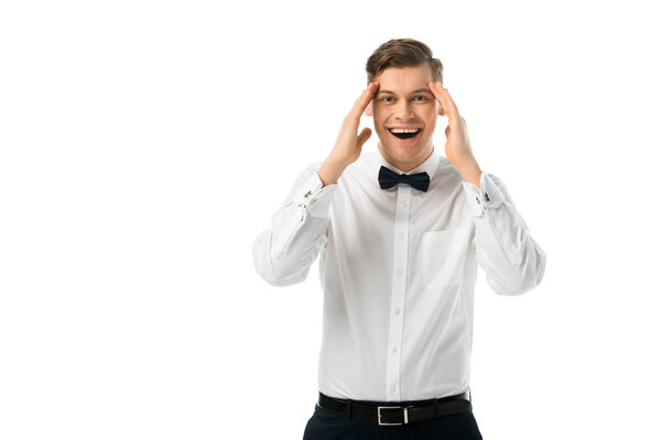 cheerful bridegroom holding hands near head isolated on white